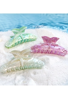Detailed close-up of three starfish hair claws with pearls on white sand beach background