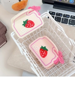 Détail de pinces à cheveux à nœud rose et imprimé fraise dans un mini panier