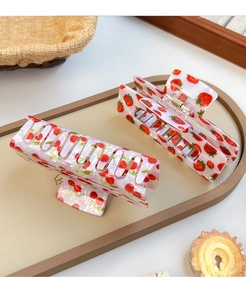Dettaglio di mollette per capelli a fiori con stampe ciliegia e fragola su vassoio