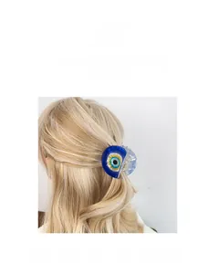 Détail d'une pince à cheveux Œil Bleu en acrylique sur des cheveux blonds ondulés