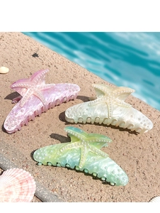 Detailed shot of starfish shark hair claws with inlaid pearls on beach sand and water
