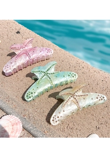 Macro shot of starfish hair claws with rhinestones on a stone surface by the pool