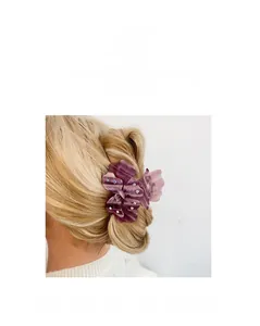 Détail d'une pince à cheveux trèfle en résine violette ornée de strass sur les pétales