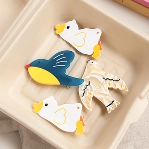 Cute bird and duck shaped acetate hair clips set displayed in a beige ceramic tray