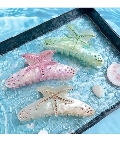 Close-up of three starfish hair claws in mint, pink, and white with rhinestones