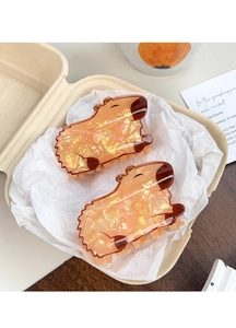 Close-up of amber marble Capybara hair claw clips set in cozy warm aesthetic packaging