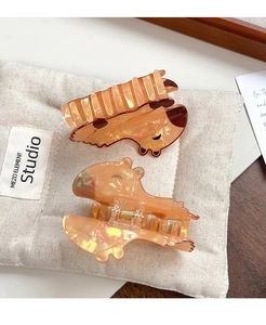 Detailed macro view of amber resin bear hair claw and wavy clip on fabric storage bag