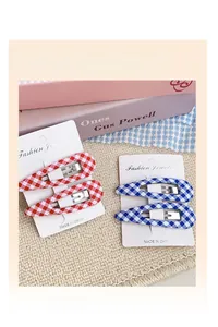 Detail view of red and blue checkered fabric snap hair clips on white card holder