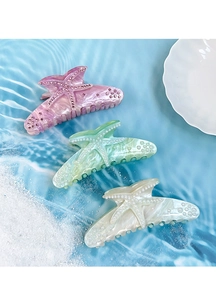 Detailed view of starfish claw clips with rhinestones and pearls on a blue water background