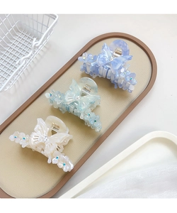Trois élégantes pinces à cheveux papillon avec strass colorés dans un plateau décoratif