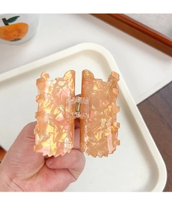 Close-up of orange opalescent acetate hair claw clip with colorful flake texture