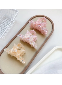 Détail de trois pinces à cheveux papillon en rose et beige avec strass sur un plateau