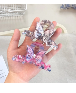 Détail d'une pince à cheveux papillon en acrylique avec strass goutte d'eau et ressort