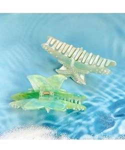 Detail of star-shaped and butterfly hair claws with pearls on a summer beach background