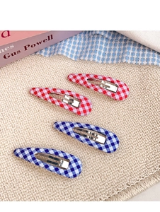 Close-up of four red and blue plaid fabric BB hair clips on soft beige textile background