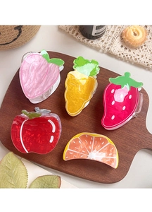 Close-up of fruit shaped hair claws including peach and strawberry on a wooden tray