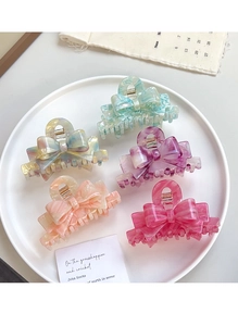 Detail view of colorful acetate bow hair claws in mint green and pink marble texture