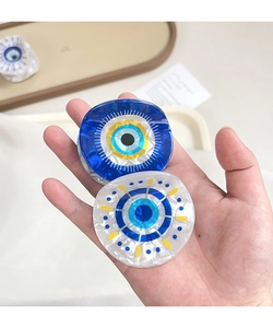 Détail de pinces à cheveux œil protecteur bleu effet verre, tenues dans la main
