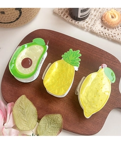 Detail of avocado, pineapple, and lemon hair claws with pearlescent finish on wooden tray