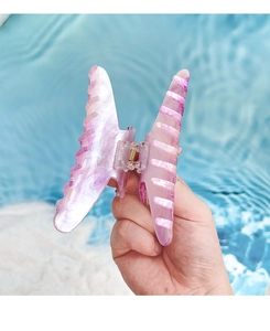 Detail of a large acrylic butterfly hair claw with pearlescent marble texture held over water