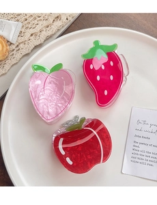 Detail of peach, strawberry and apple fruit hair claws on a white ceramic plate