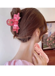 Detailed back view of a pink acetate bow hair claw clip styled on a woman's bun hairstyle