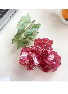 Détail des pinces à cheveux trèfle en acétate avec strass colorés sur un bureau blanc
