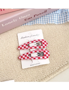 Detail view of a pair of red and white plaid fabric snap hair clips on a display card