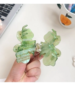 Gros plan d'une pince à cheveux papillon verte translucide montrant la taille