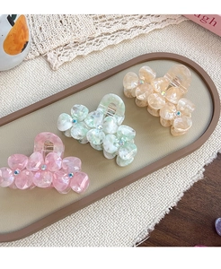 Three-piece acetate flower hair claws set with rhinestones on a decorative lace display