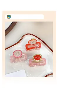 Three fruit-shaped hair claws including apple, dragon fruit and watermelon on a white tray