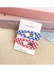 Detail of blue and red plaid fabric BB hair clips on a white fashion jewelry display card