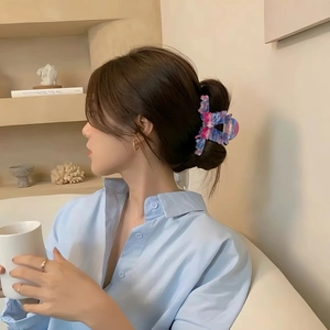 Pince à cheveux papillon dégradé rose et bleu portée sur un chignon de femme