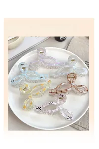 Dettaglio di 6 mollette per capelli a quadretti colorati in un piatto di ceramica