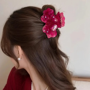 Pince à cheveux trèfle rose rouge élégante avec strass sur cheveux bruns ondulés