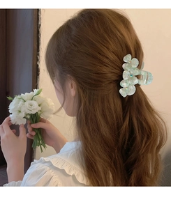 Detail of mint green floral acetate hair claw clip with rhinestones worn on hair