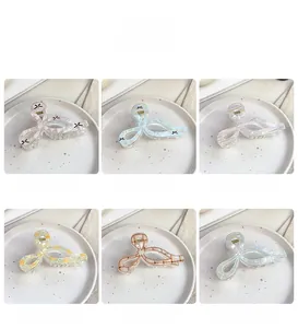 Dettaglio di sei mollette a fiocco colorate con motivi a scacchi su vassoio in ceramica