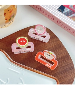Detailed shot of three fruit-themed hair claws featuring watermelon and apple patterns