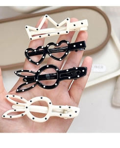 Détail de barrettes à pois noirs et blancs en forme de couronne, de cœur et de lapin