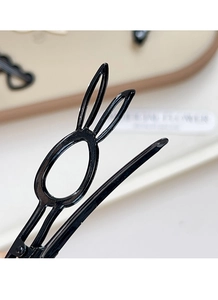 Détail d'une pince à cheveux noire brillante en forme de lapin avec finition métallique