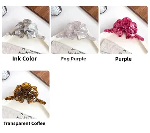 Dettaglio di 4 grandi fermagli per capelli in acetato nei colori grigio, viola e ambra