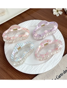 Détail de quatre pinces à cheveux à motif marguerite pastel sur une assiette en céramique