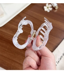 Gros plan d'une grande pince à cheveux papillon transparente avec ressort en métal doré