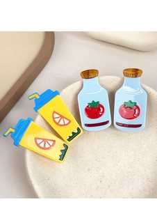 Detailed macro view of cute acrylic juice and tomato hair clips in a ceramic dish