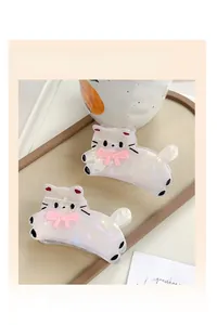 Détail de pinces à cheveux chat blanc nacré avec des nœuds roses sur un plateau