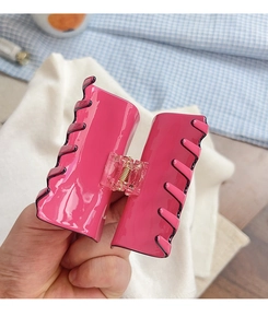 Detail einer pinken Haarklammer mit schwarzen Wellenmustern und Metallfedermechanismus