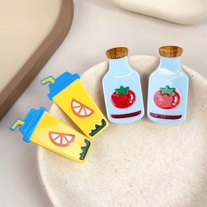 Set of four cute cartoon tomato and orange juice acrylic hair clips on a ceramic tray