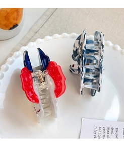 Detail of cute astronaut pattern hair claw clips with marble texture on white tray