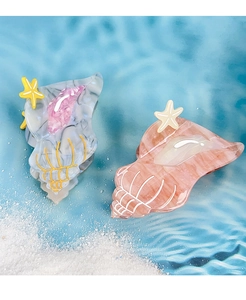 Detailed close-up of acetate conch shell hair claw clips with starfish on sand