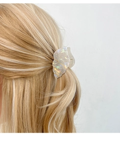 Detail of shell-shaped acetate hair claw with pearlescent finish and gold vein texture